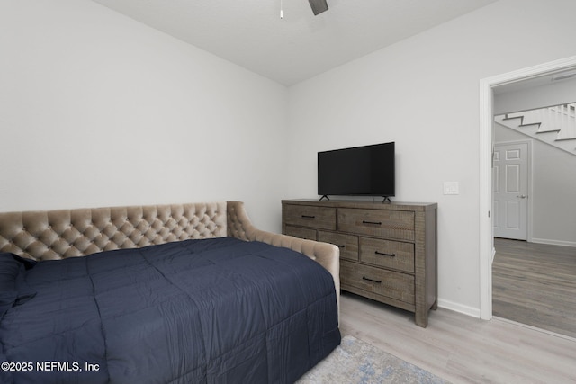 bedroom with light wood finished floors, a ceiling fan, and baseboards