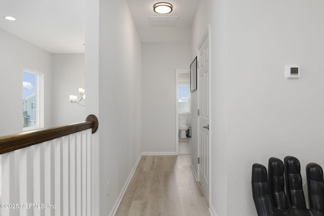 hallway featuring light wood-type flooring, visible vents, and baseboards