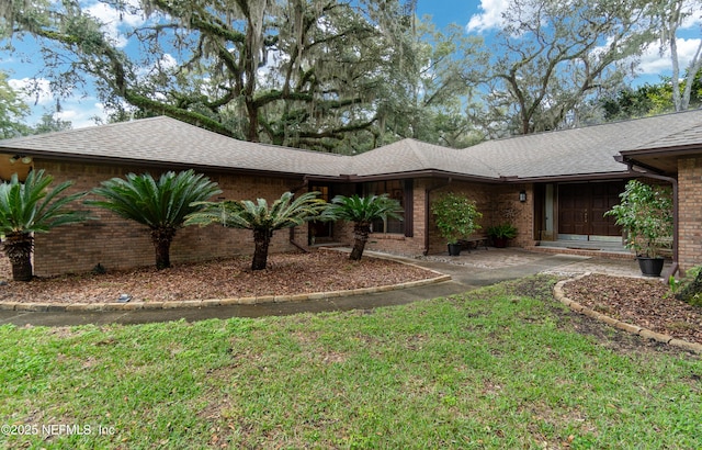 exterior space with brick siding, a lawn, and a shingled roof