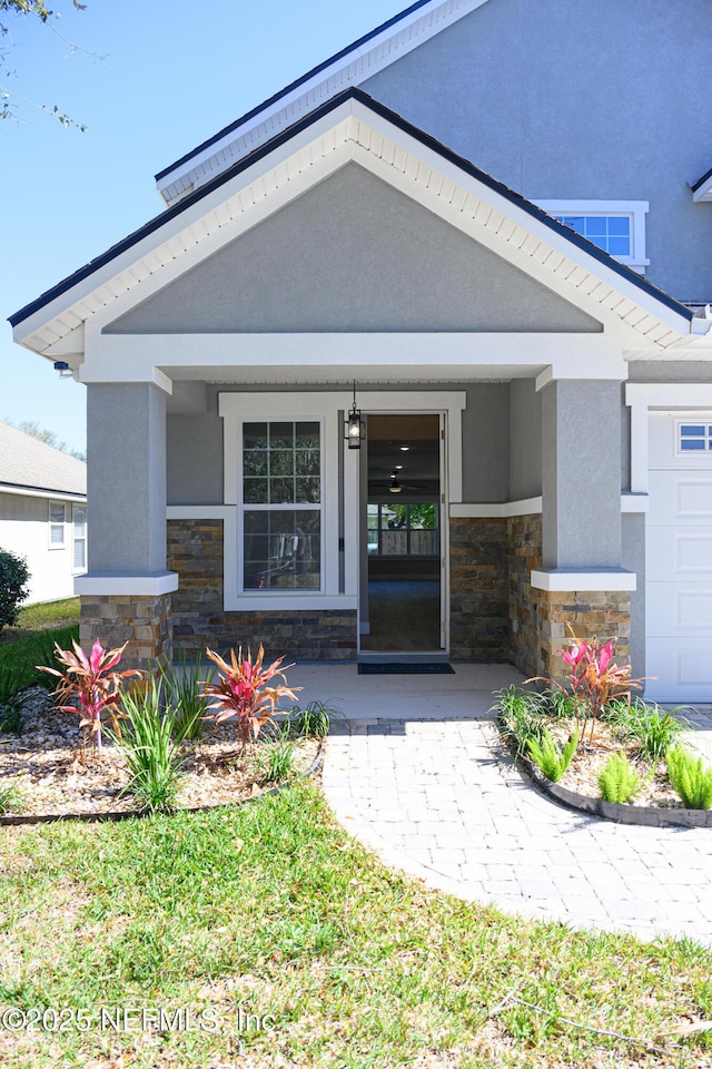 doorway to property featuring stucco siding, stone siding, and a garage