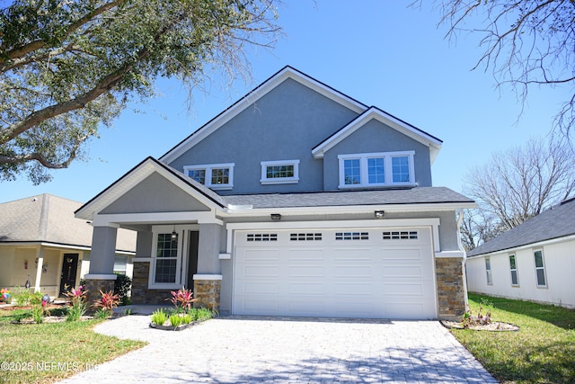 craftsman inspired home with stone siding, stucco siding, an attached garage, and decorative driveway