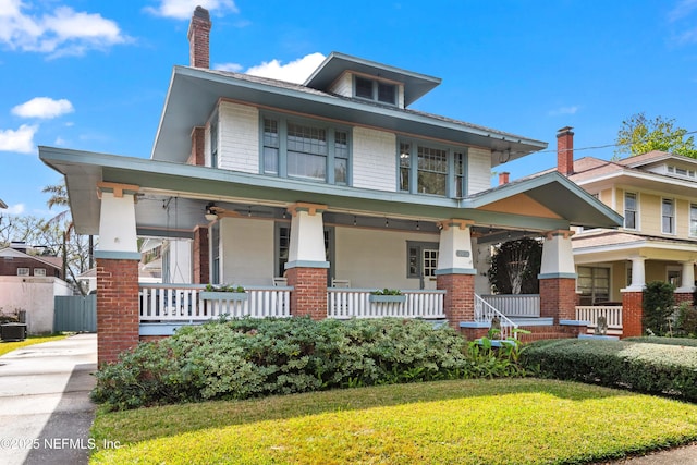 traditional style home with covered porch, a front yard, and brick siding