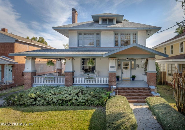 traditional style home featuring a porch, a chimney, and brick siding