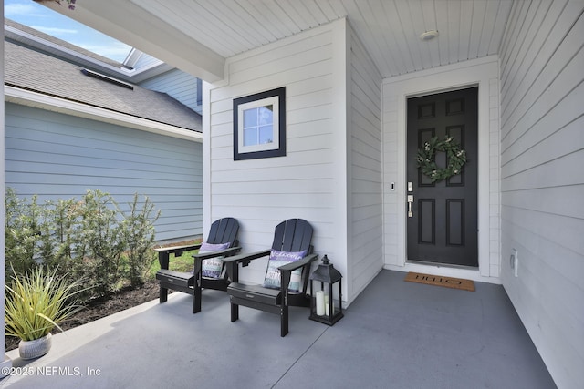 view of exterior entry with a shingled roof and a porch