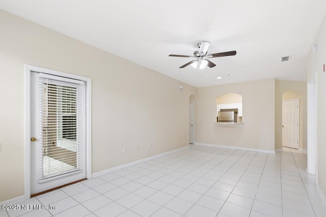 spare room with light tile patterned floors, visible vents, arched walkways, baseboards, and ceiling fan