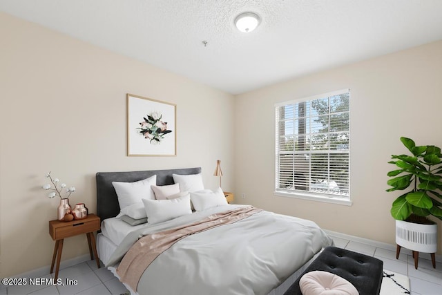 bedroom with a textured ceiling, light tile patterned flooring, and baseboards