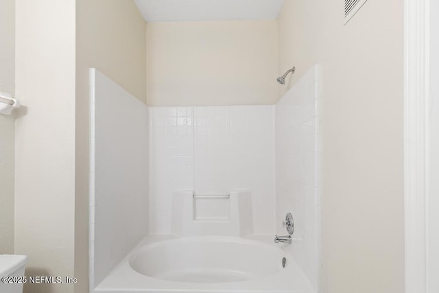 bathroom featuring toilet, visible vents, and washtub / shower combination