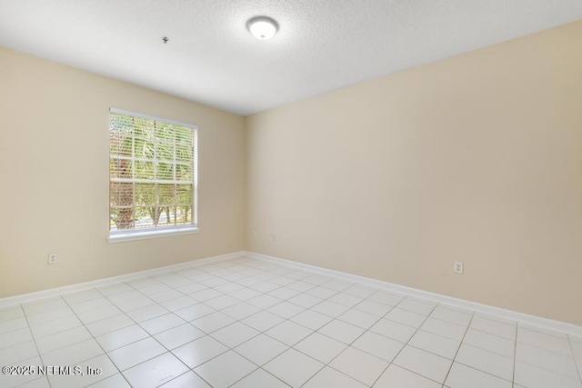 spare room featuring light tile patterned flooring, a textured ceiling, and baseboards