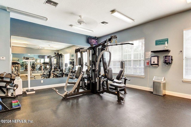 workout area with a textured ceiling, visible vents, and baseboards