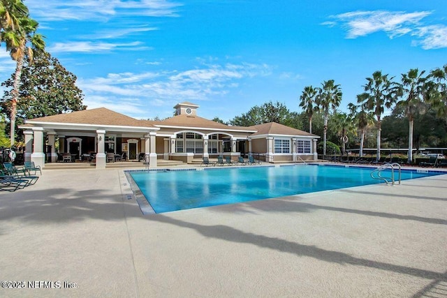 community pool with a patio area and fence