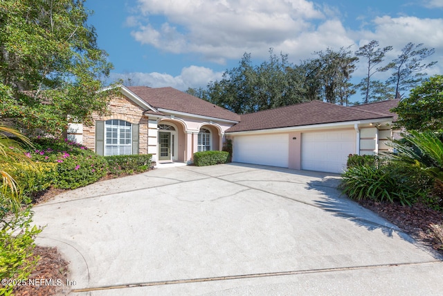 view of front of house with stone siding, driveway, and stucco siding