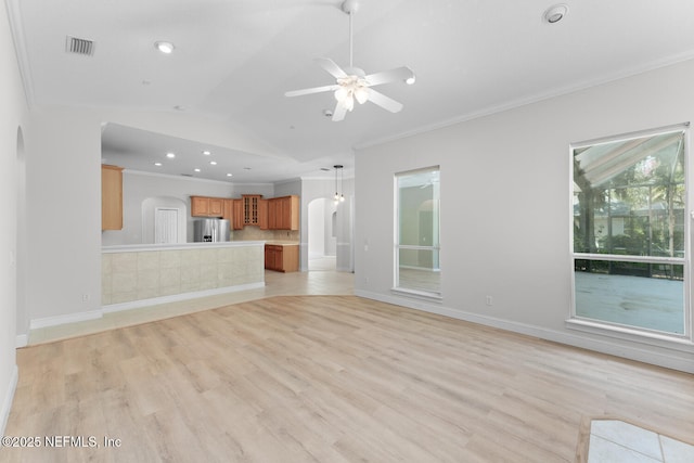 unfurnished living room with light wood finished floors, baseboards, visible vents, vaulted ceiling, and crown molding