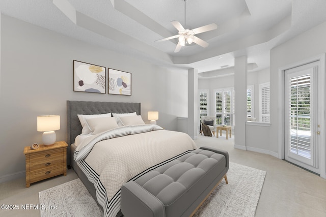 bedroom with access to exterior, a tray ceiling, light colored carpet, ceiling fan, and baseboards