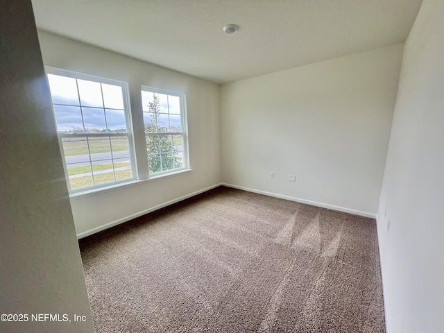 carpeted empty room featuring baseboards