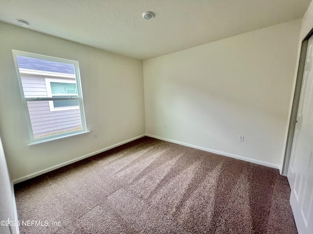 carpeted spare room featuring baseboards