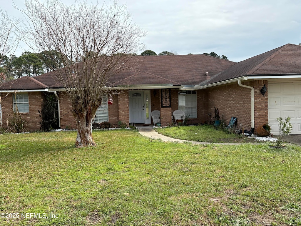 single story home with an attached garage, a shingled roof, a front lawn, and brick siding