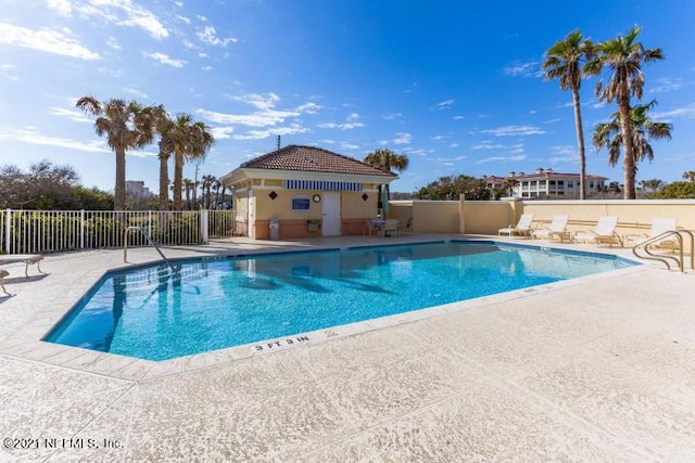 community pool with fence and a patio