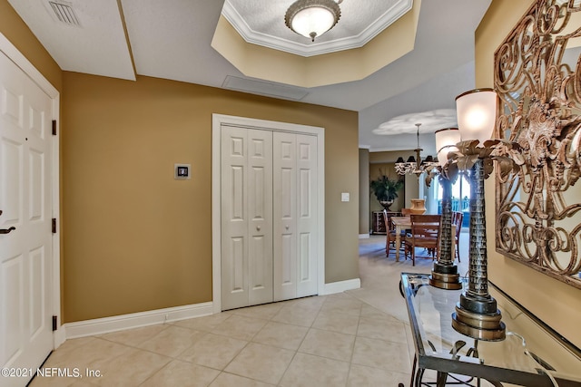 entryway featuring light tile patterned floors, a chandelier, visible vents, baseboards, and a raised ceiling