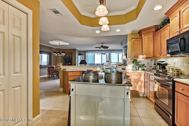 kitchen featuring a tray ceiling, pendant lighting, a kitchen island, and black appliances