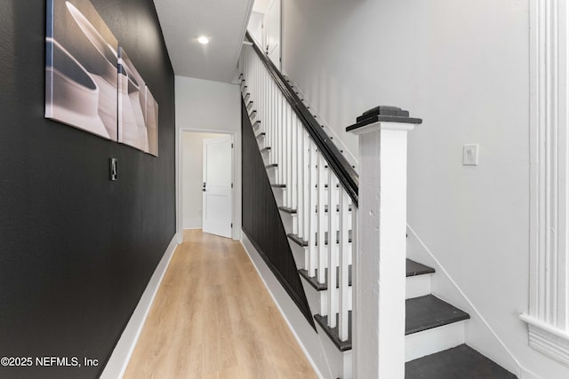 staircase featuring baseboards and wood finished floors