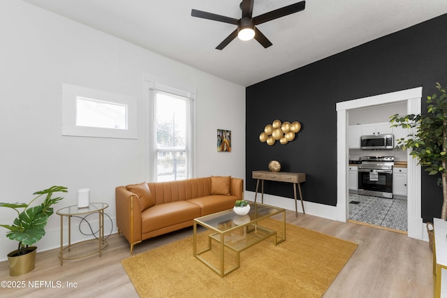 living room with a ceiling fan, light wood-type flooring, and baseboards