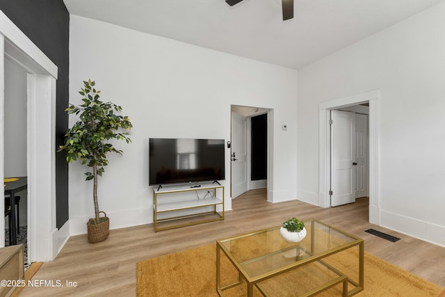 living area featuring ceiling fan, wood finished floors, visible vents, and baseboards