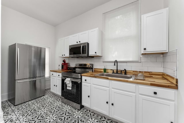 kitchen featuring wooden counters, appliances with stainless steel finishes, a sink, and white cabinetry