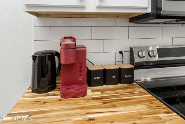 interior details with tasteful backsplash, stainless steel electric range, and wood counters