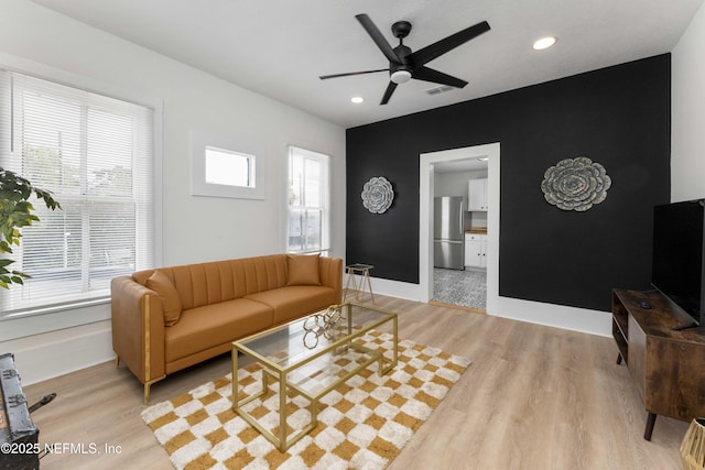 living area with baseboards, plenty of natural light, visible vents, and light wood-style floors