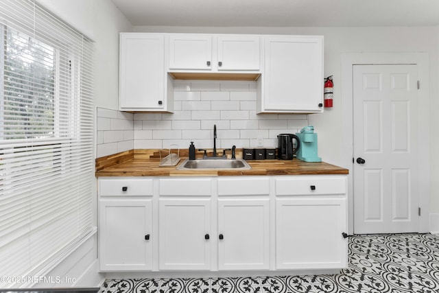 kitchen with white cabinetry, wooden counters, backsplash, and a sink