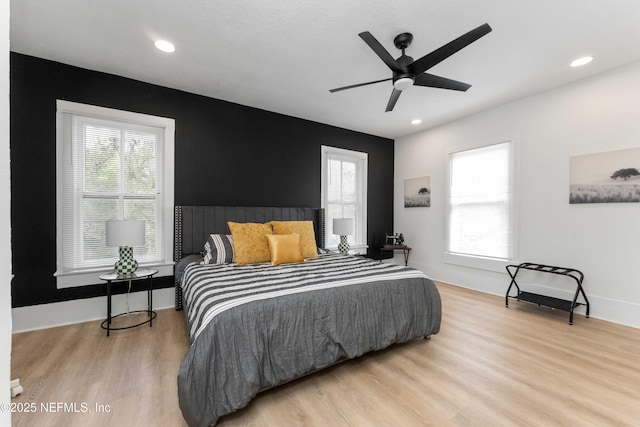 bedroom featuring light wood-style flooring, multiple windows, and baseboards