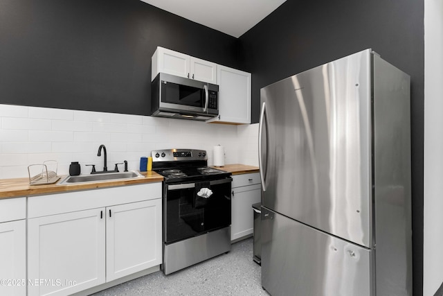 kitchen featuring wooden counters, appliances with stainless steel finishes, a sink, and white cabinets