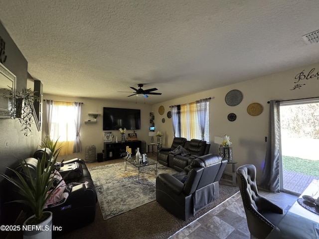 living area with a textured ceiling, ceiling fan, and visible vents