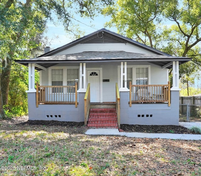 bungalow-style house featuring covered porch, roof with shingles, crawl space, and fence