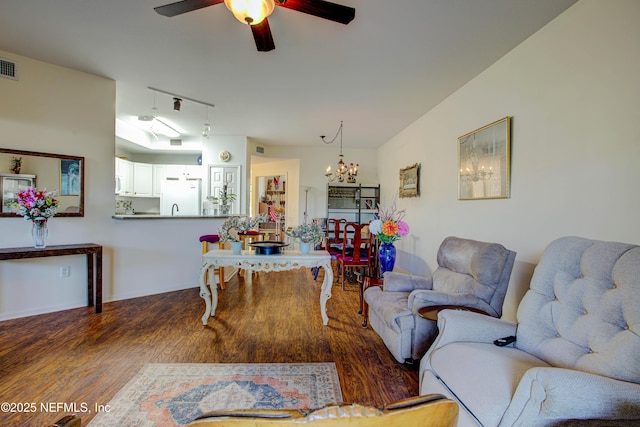 living area with ceiling fan with notable chandelier, visible vents, track lighting, and wood finished floors