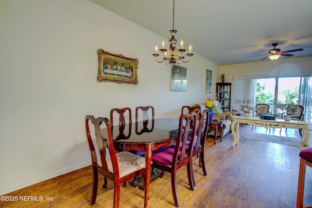 dining space with ceiling fan with notable chandelier, baseboards, and wood finished floors