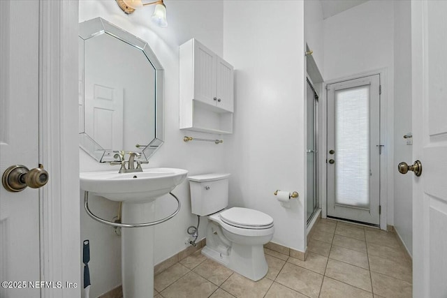 full bathroom featuring a stall shower, baseboards, toilet, and tile patterned floors