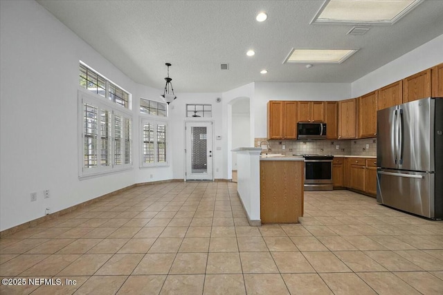 kitchen with light countertops, appliances with stainless steel finishes, brown cabinetry, and tasteful backsplash