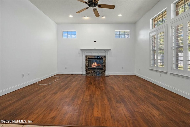 unfurnished living room with baseboards, ceiling fan, a premium fireplace, wood finished floors, and recessed lighting