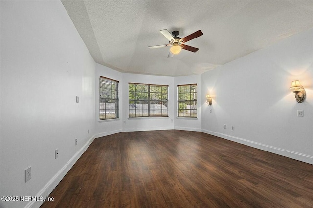 unfurnished room featuring a textured ceiling, dark wood-style flooring, a ceiling fan, and baseboards