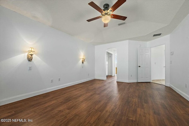 interior space with arched walkways, wood finished floors, visible vents, and baseboards