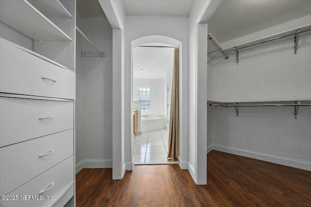 spacious closet with arched walkways and wood finished floors