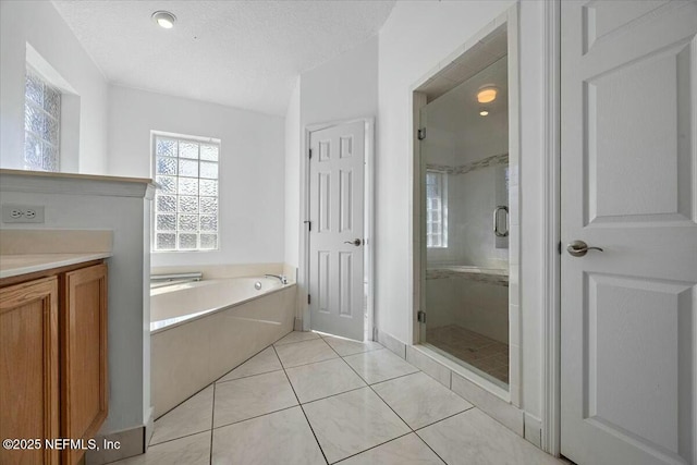 bathroom featuring a stall shower, tile patterned flooring, a garden tub, and a textured ceiling