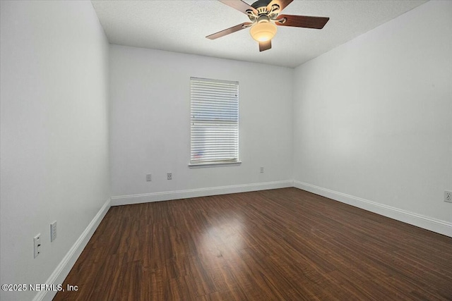 empty room with ceiling fan, dark wood finished floors, and baseboards