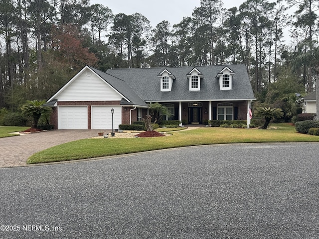 cape cod home with a garage, brick siding, roof with shingles, decorative driveway, and a front yard