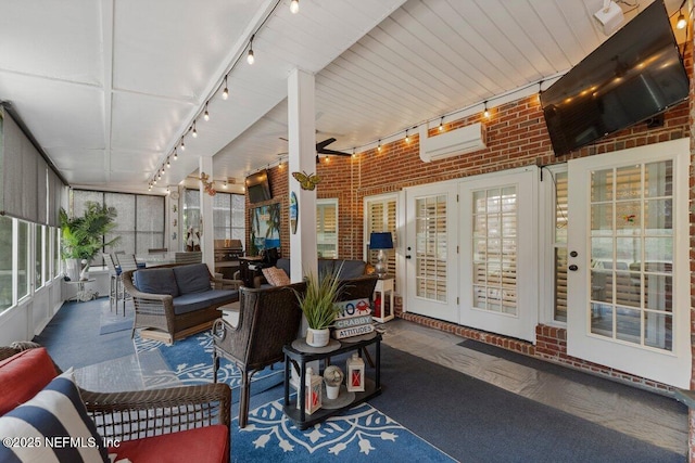 sunroom featuring a wall unit AC and track lighting