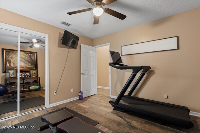 workout area with baseboards, visible vents, and wood finished floors