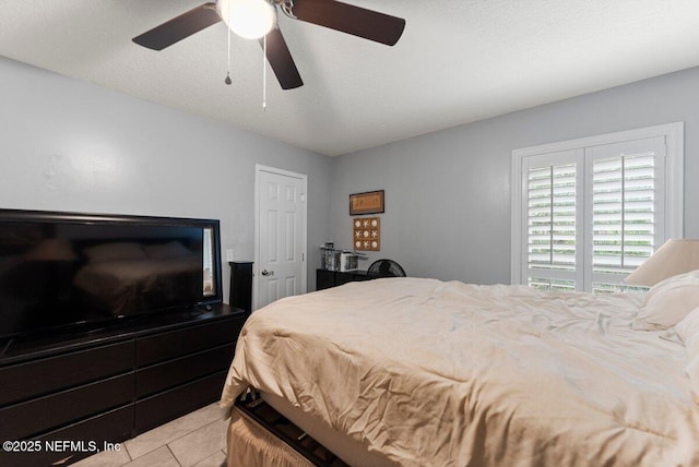 bedroom featuring a textured ceiling, ceiling fan, and light tile patterned flooring