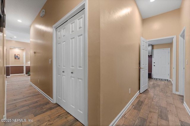 hallway with recessed lighting, wood finished floors, and baseboards