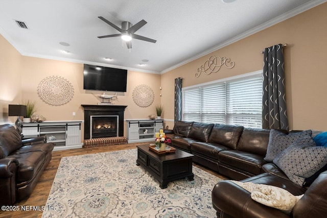 living area with ornamental molding, a fireplace, wood finished floors, and visible vents